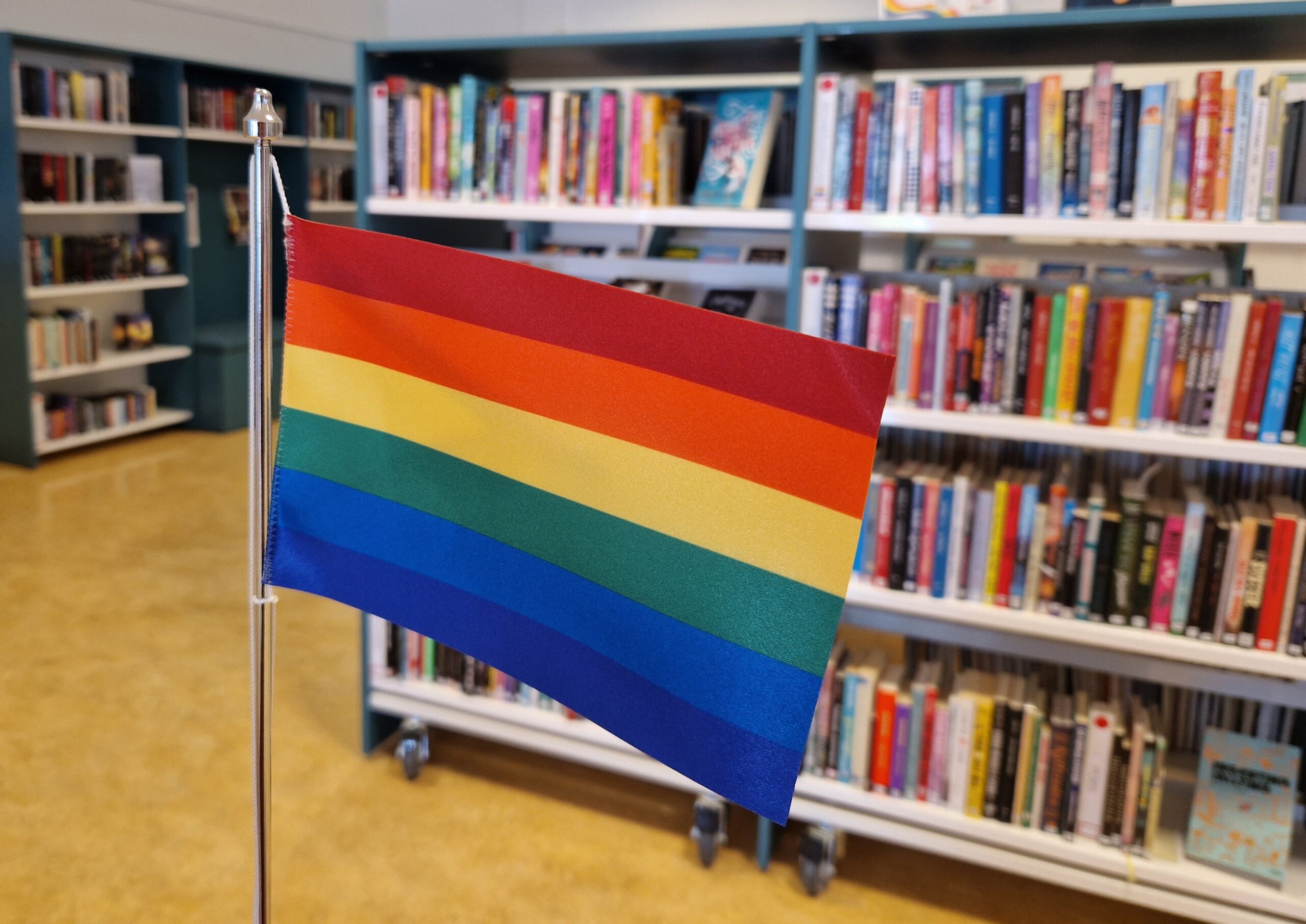 Regnbågsflaggan framför en bokhylla