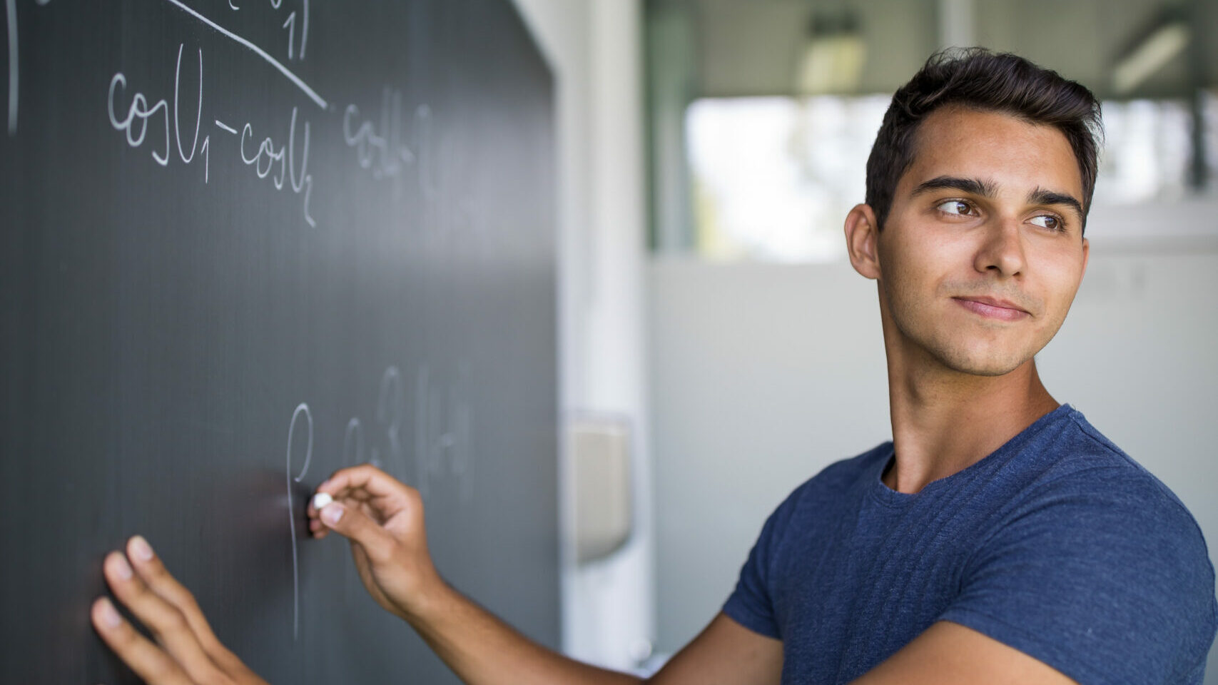 En lärare skriver på svarta tavlan i klassrummet