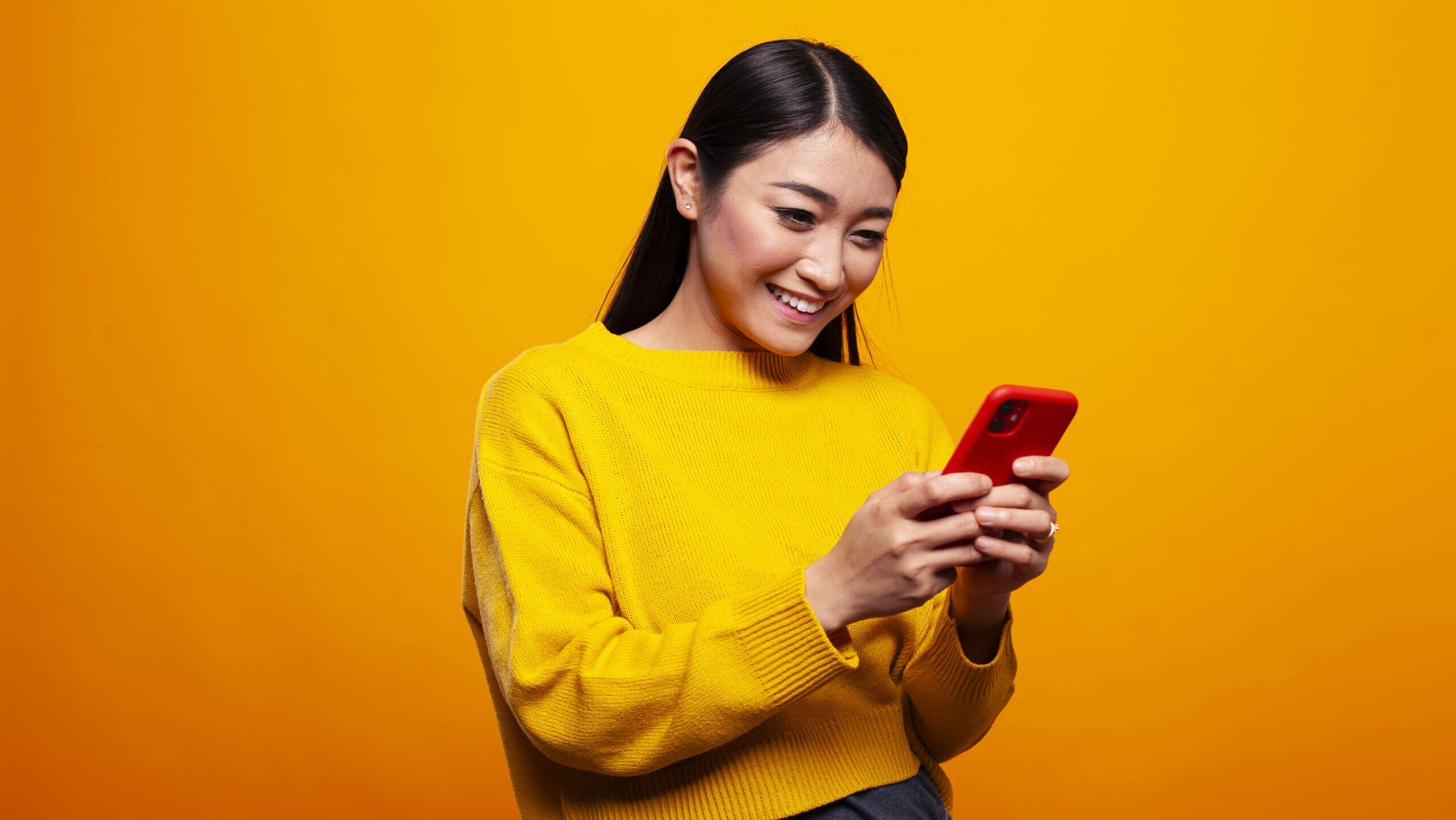 En kvinna tittar på sin mobiltelefon och hon ser glad ut