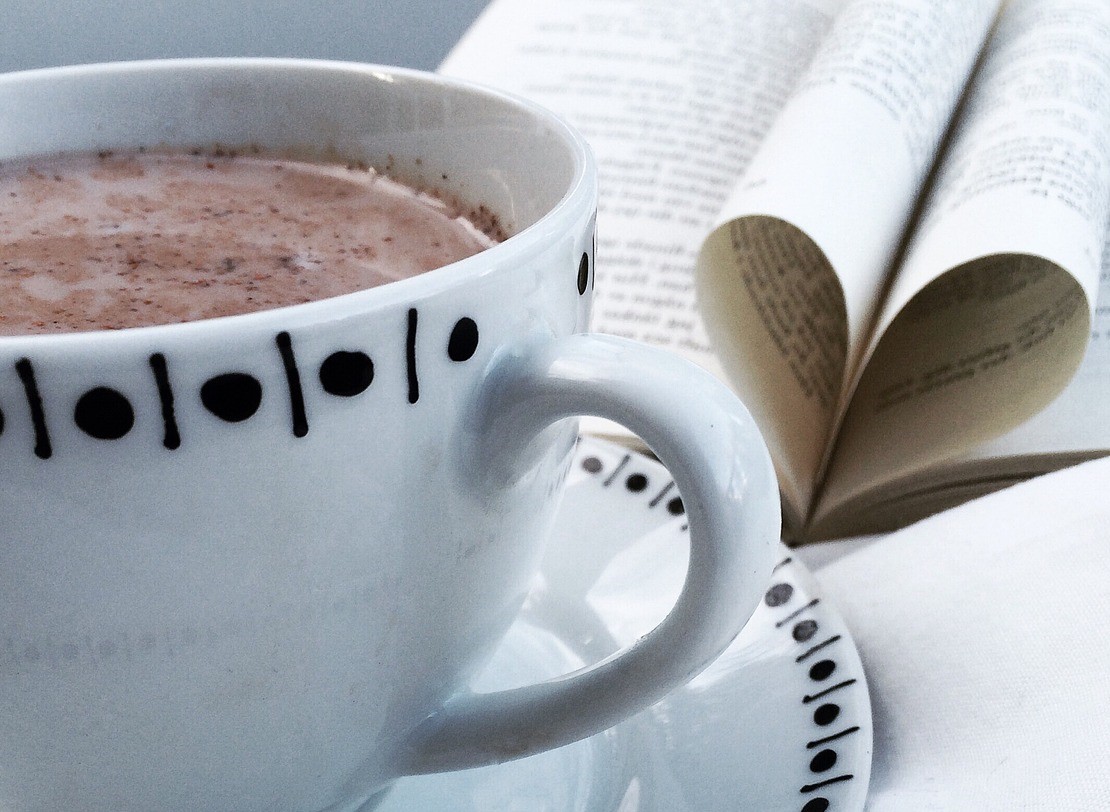 Kaffekopp och en uppslagen bok med sidor formade till ett hjärta.