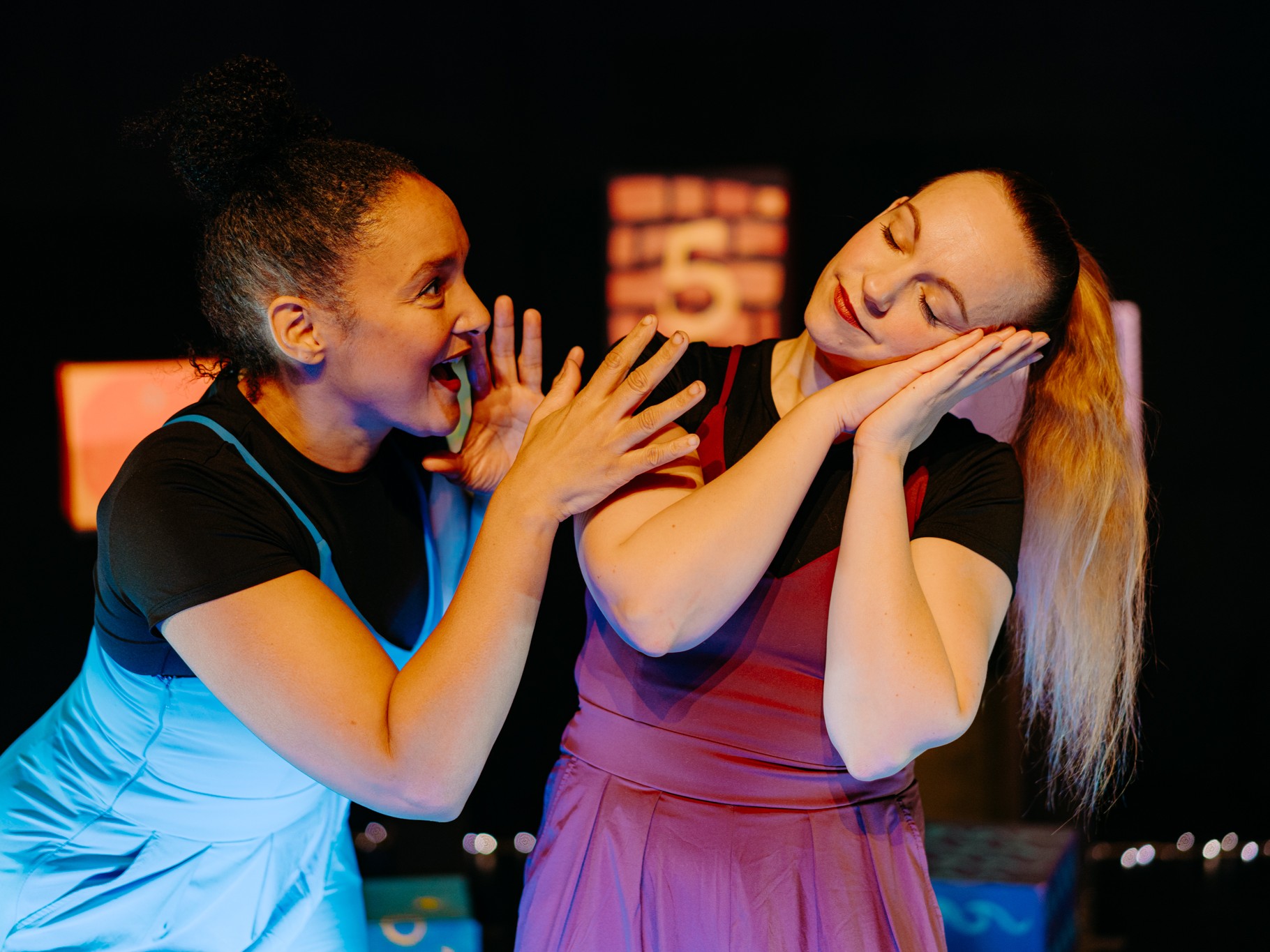 En kvinna säger något till en annan kvinna som lutar huvudet mot sina händer.