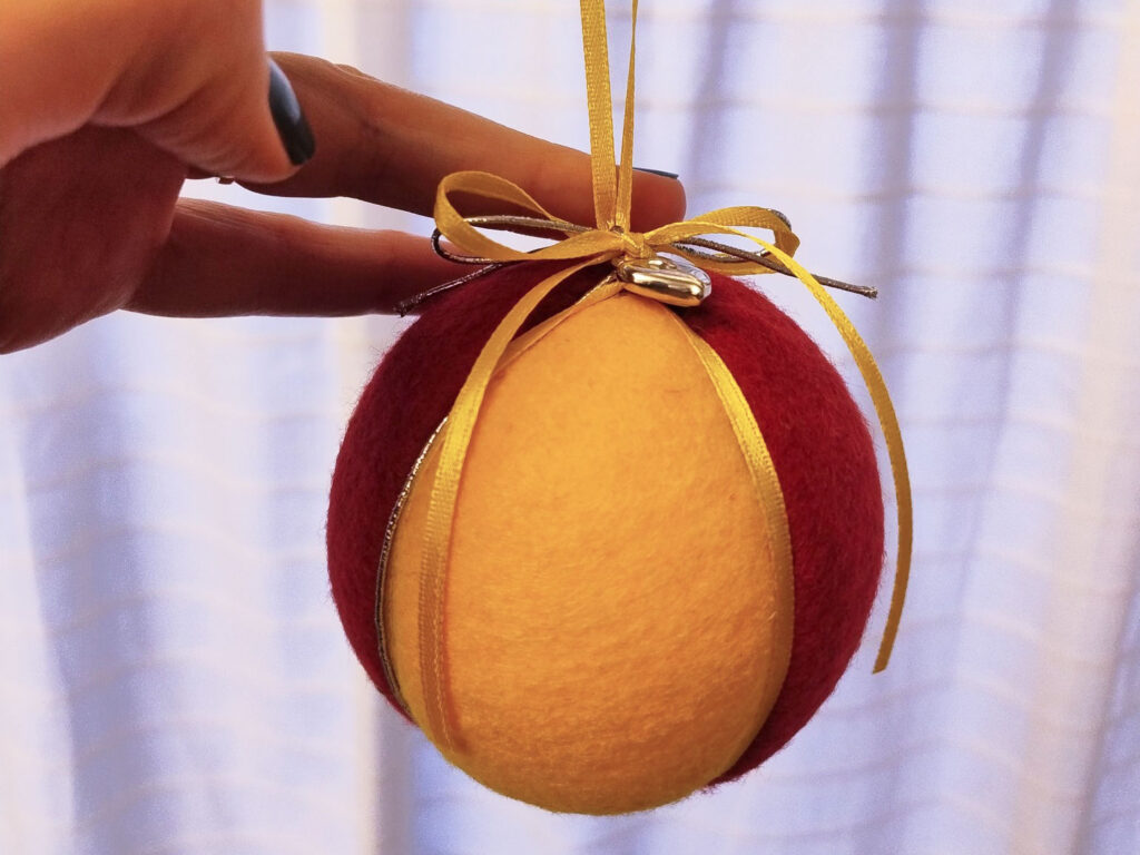 Hemmagjord julkula i röd och gul filt.