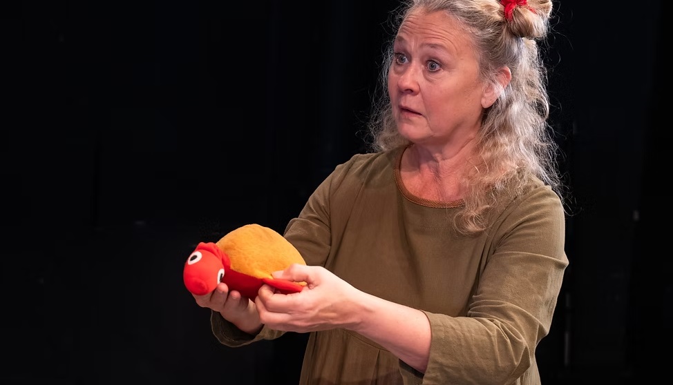 en kvinna som håller upp ett gosedjur mot en svart bakgrund