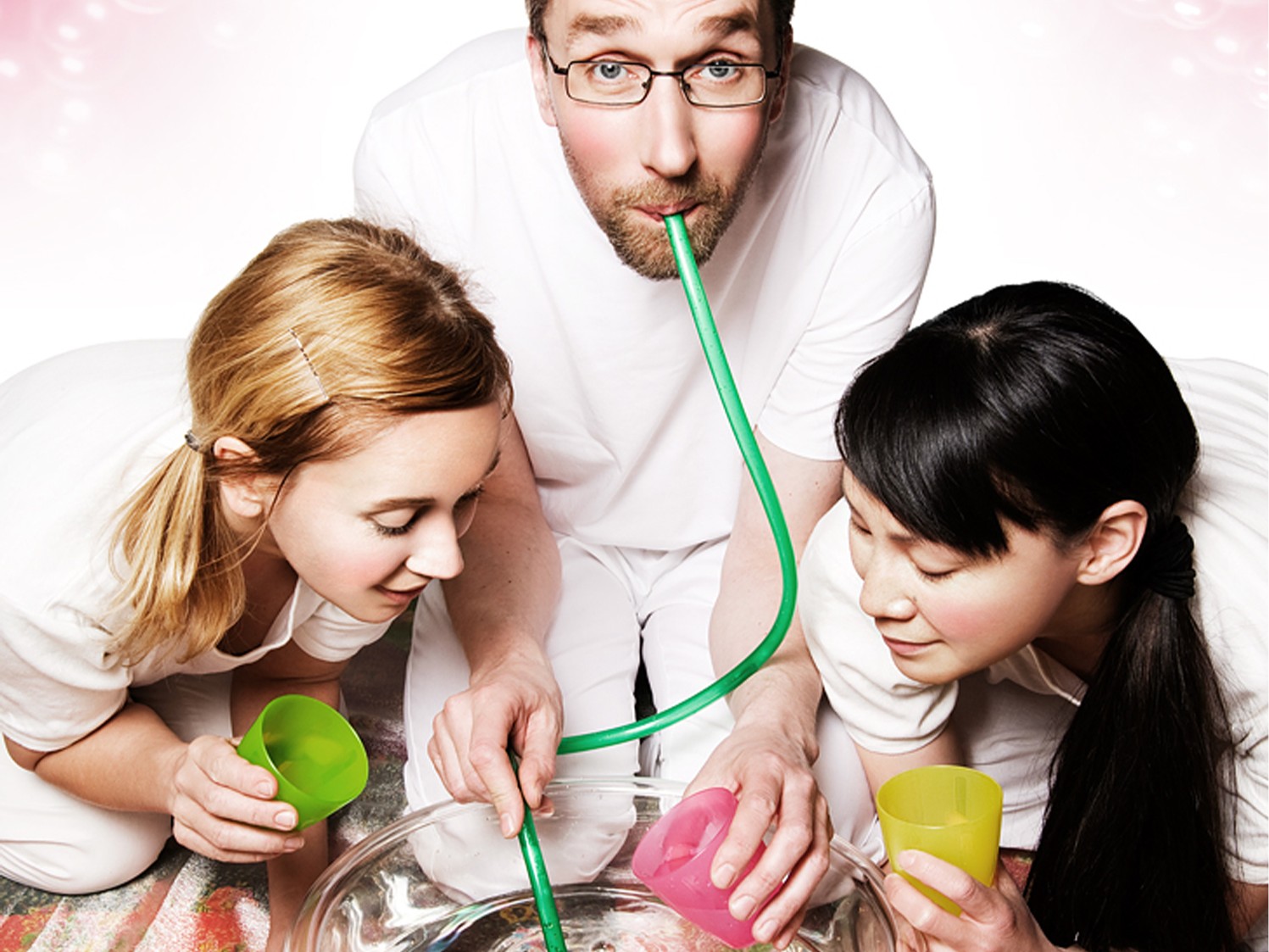 Tre personer gör ett experiment med en skål vatten och en slang.