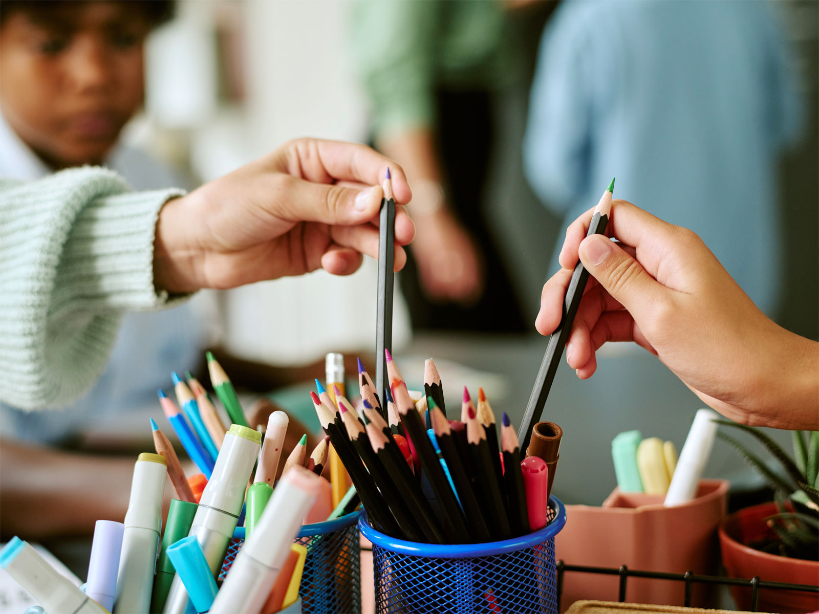 Barn plockar färgpennor ur ett pennställ.