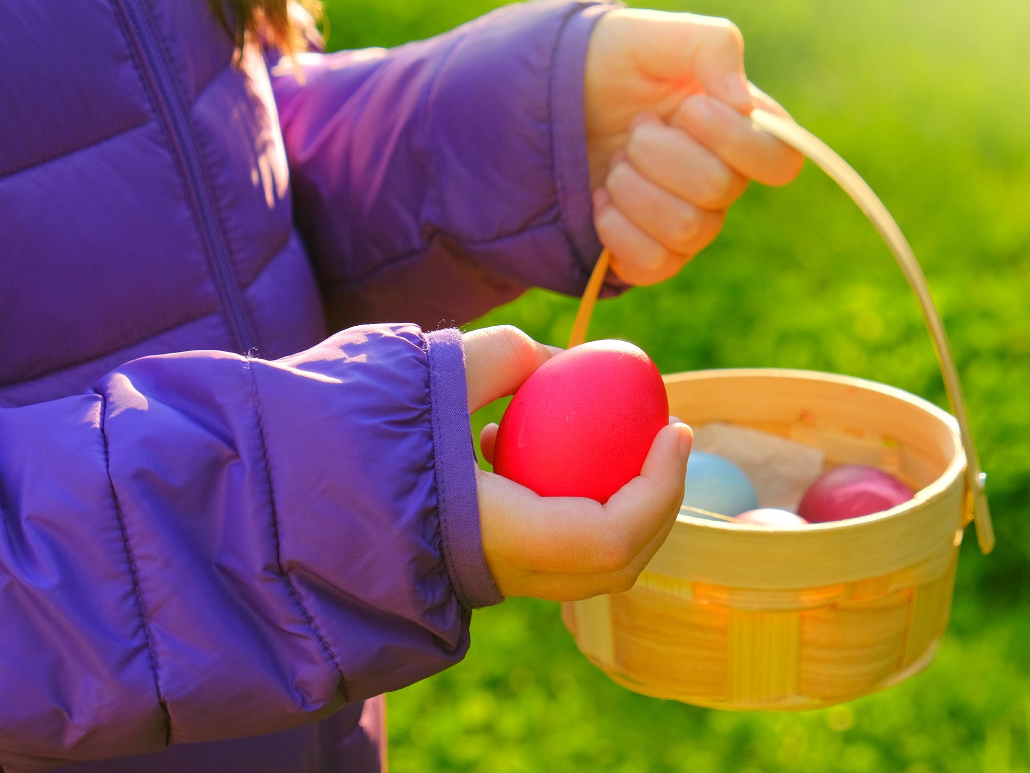 Ett barn håller ett rött ägg i handen och en äggkorg i den andra.