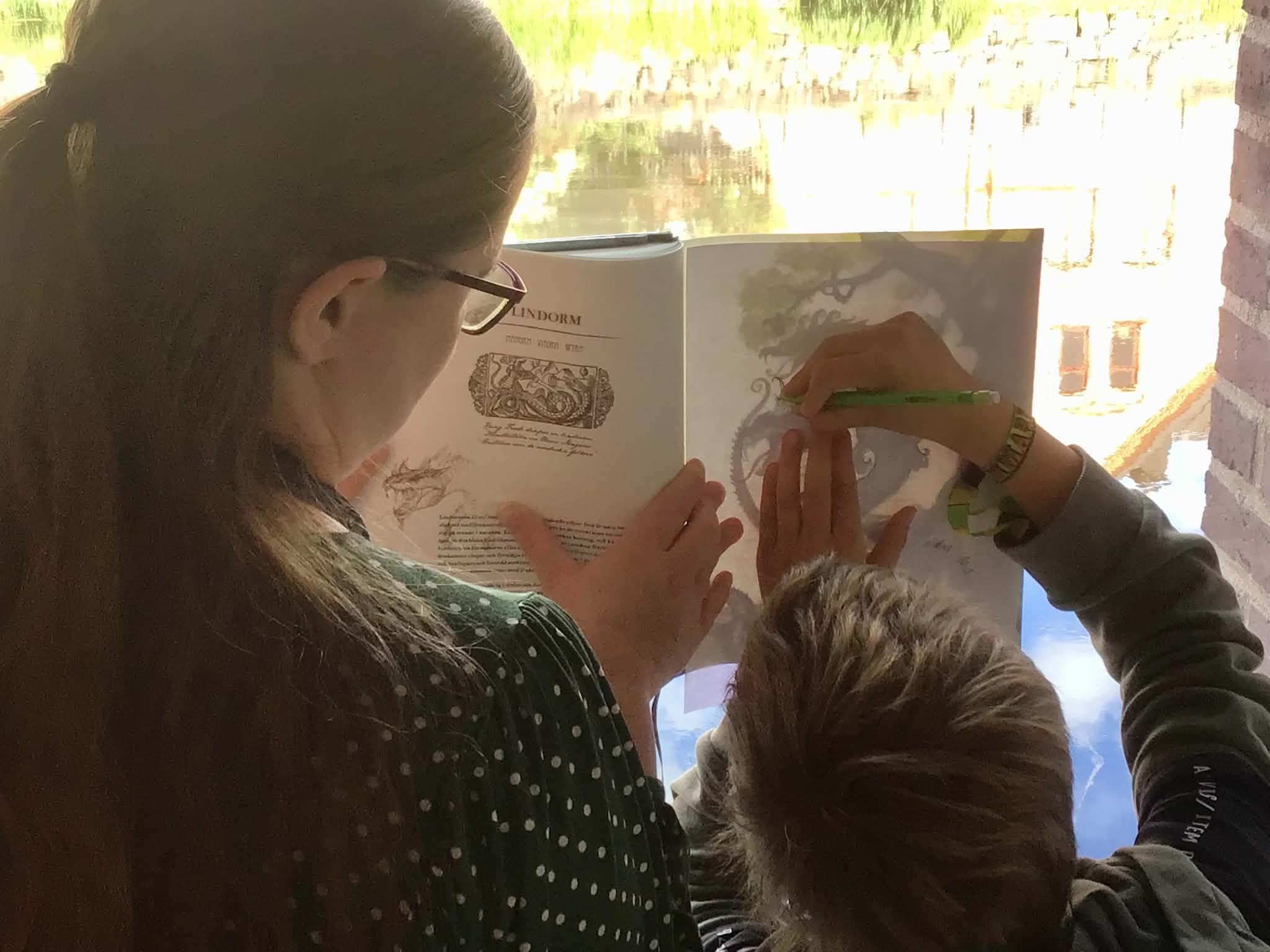 Två personer tittar i bok.
